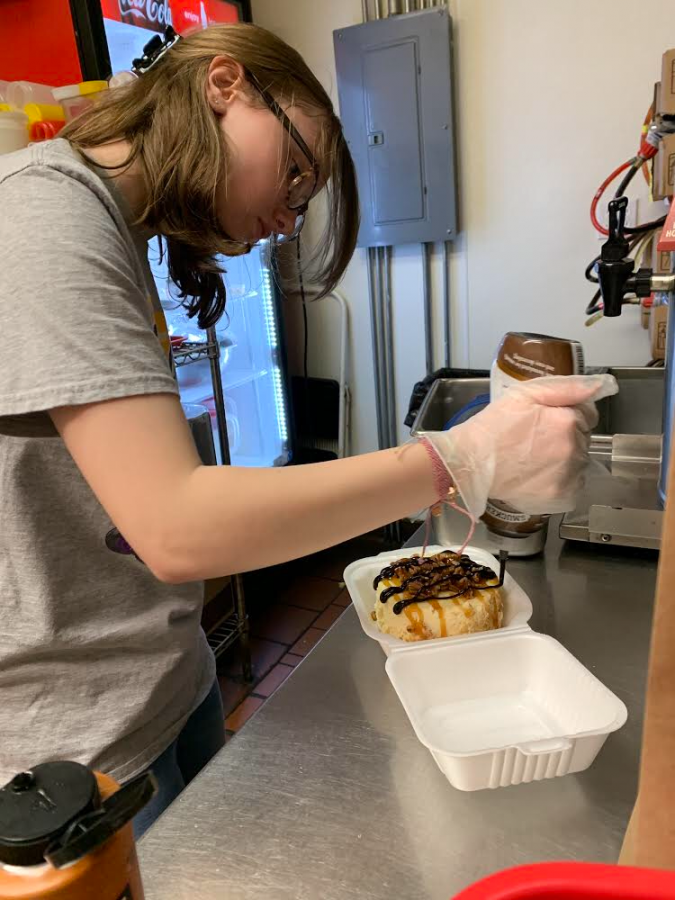 Senior Cara Folsom decorates a cheesecake at her familys family-run restaurant, Emerys. Folsom is able to pitch in to help after the stay-at-home order. 